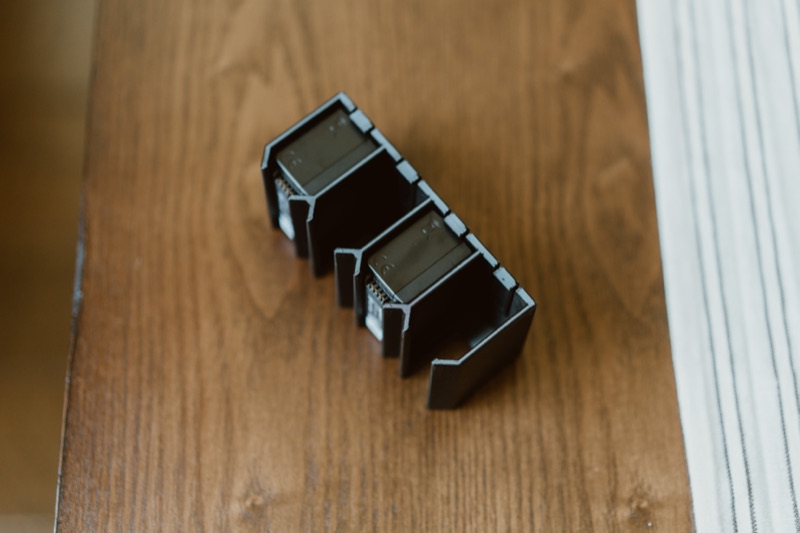 Two batteries in the holder on a wood desk, seen from above