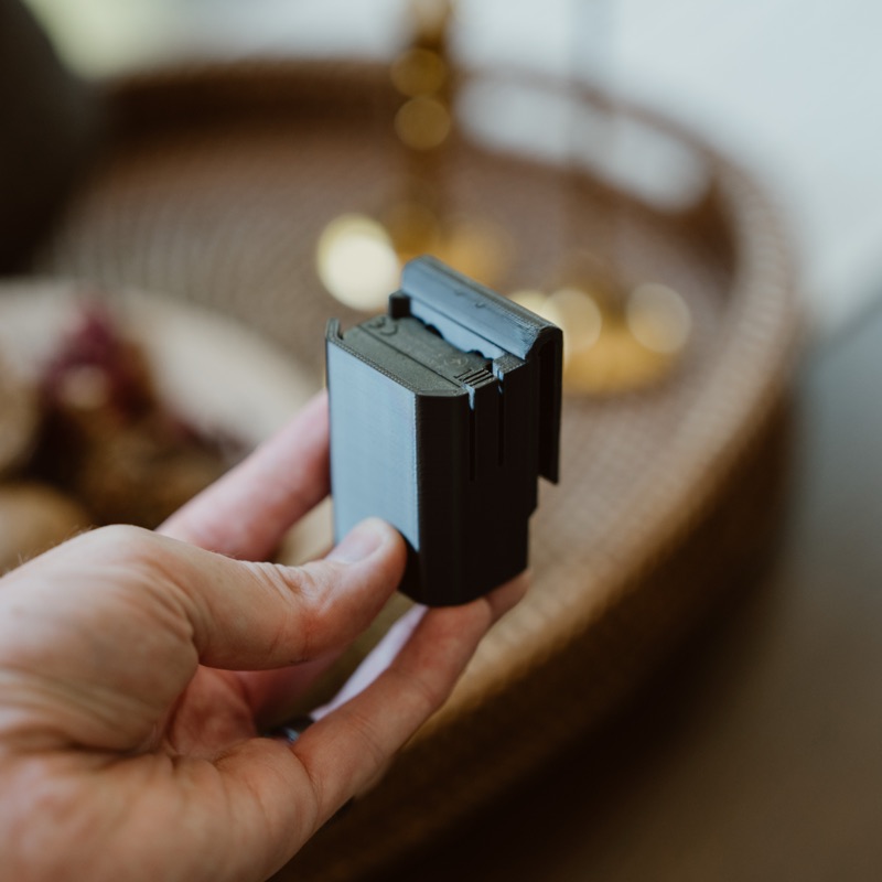 A battery seated in the belt clip, held in a hand